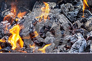 Red-hot pieces of coal and flames in a cooking brazier.