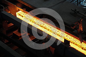 Red hot steel metal billets after molten steel casting.  Continuous casting machine. Background of the blacksmith and