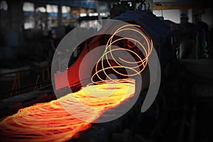 Red hot steel metal wire rods or coils after molten steel casting.  Continuous casting machine. Background of the blacksmith and