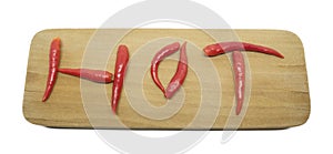 Red hot thai chilli peppers in a word hot on a cutting board