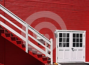 Red house exterior with white doors and stairs