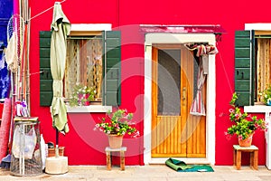 Red house with flowers and plants. Colorful house in Burano island near Venice, Italy