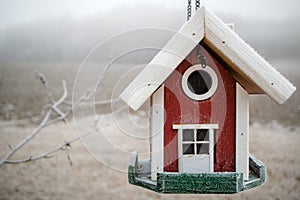 Red house-like bird feeder with frost