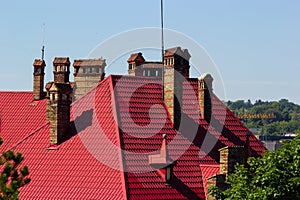 Red house roof with red brick chimney. Ceramic chimney, metal roof tiles, gutters