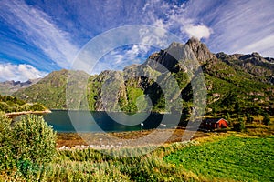 Red house on the shore of lake with view to mountains in the Norway at summer