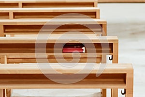 Red hymnbook under the prayer kneeling table in the church