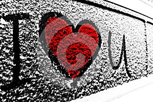 Red I love you Heart symbol on frozen window of the car. Shape of heart drawn on snow on front window of the car. Heart snow. Chri