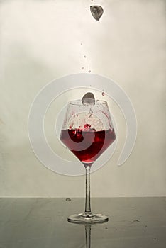A red iced drink is poured into a glass with a splash