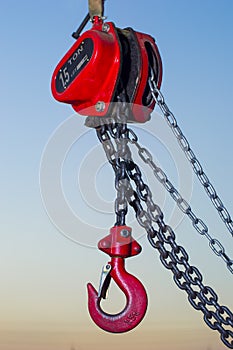 Red Industrial hook hanging on reel chain and blue sky sunset ba