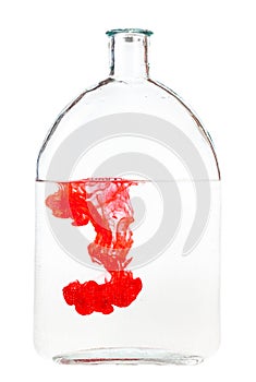 Red ink dissolves in water in glass flask isolated