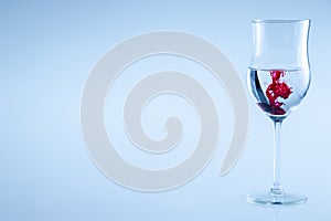 Red ink drop, wine glass with water. Half full glass wine isolated