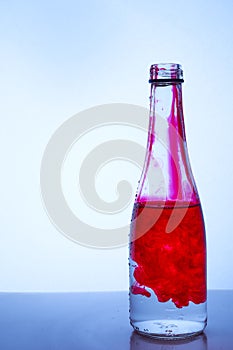 Red ink mixed with water in a glass bottle on a light background