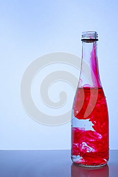 Red ink mixed with water in a glass bottle on a light background