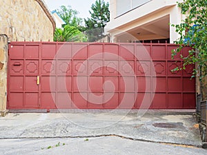 A red iron fence with a wicket, geometric pattern and sharp spiers encloses a residential building and a courtyard with