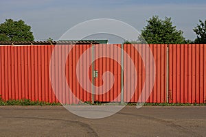 Red iron gate and metal wall fence on a rural street
