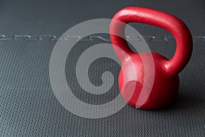 Red iron kettlebell on a black rubber gym floor, fall fitness