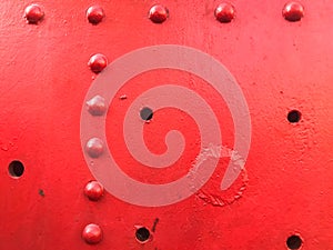 Red iron metal rough painted strong solid industrial wall with rivet holes and bolts. Background, texture