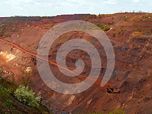 Red iron ore open-pit mine with machinery