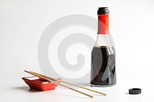 Red Japanese sauce bowl - seyuzaru, sticks - varibashi and a glass bottle with soy sauce on a white background