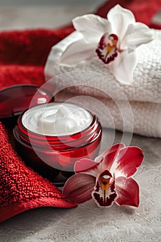 red jar with cream with towel and orchids photo