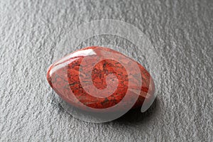 Red jasper stone on a black stone board. Closeup.