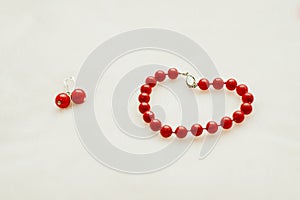 Red jewelry: bracelet and earrings with beads on a white background