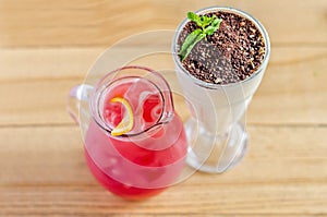 Red juice in a jug with lemon and a white cocktail in a glass with chocolate and mint