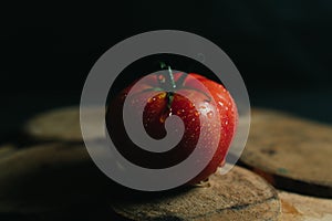 Red juicy and desirable tomato on a piece of wood on a black background photo