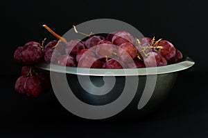 Red juicy fresh grapes with metal plate healthy snack full view on dark background