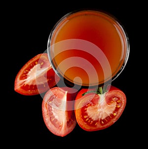 Red, juicy, fresh tomatoes and tomato juice on a black background
