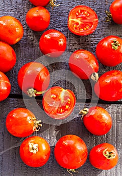 Red juicy tomatoes cherry on dark wooden board