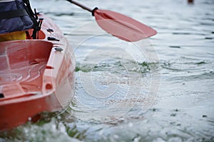 Red kayak floats on water, rear side view