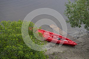 A red kayak on the river bank