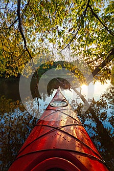 Red kayak under trees at sunset and beautiful river