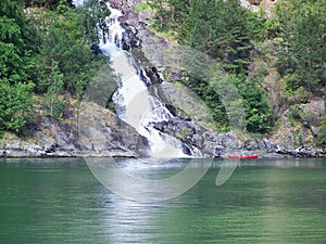 red kayak at the waterfall, nature Norway, fjord background