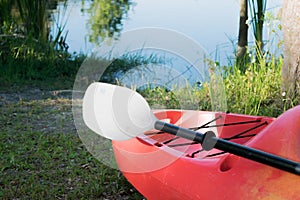 Red kayak and white paddle pointed towards water