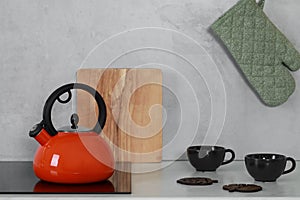 Red kettle with whistle on cooktop in kitchen. Space for text