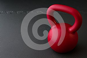 Red kettlebell on a black gym floor