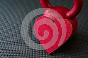 Red kettlebell on a black gym floor with large red heart