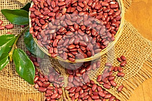 Red Kidney beans in a small woven basket on an artesan weave fabric, twenty USD bills