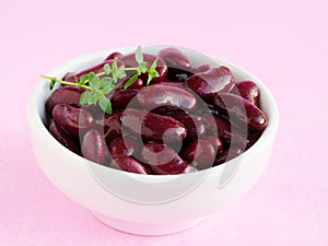 Red kidney beans in white bowl over pink background