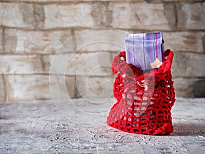 Red knitted bag with gifts, chocolate bar