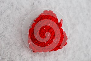 Red knitted heart in the snow