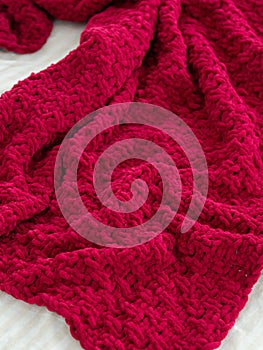 Red knitted plaid close-up. Background. Creases on soft surfaces