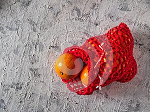 Red knitted reusable pouch with tangerinesRed knitted reusable pouch with tangerines on a light background