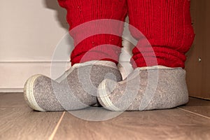 Red knitted socks and woolen slippers on the feet