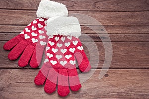 Red knitted winter gloves on wooden surface