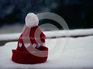 Red knitted winter hat in the snow