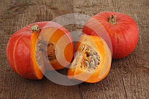 Red kuri squashes on a rough woody texture background.