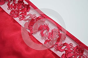 Red lace element of silk satin fabric on white background. Decorative finishing of women\'s clothing, lingerie